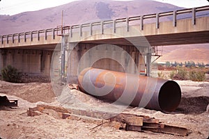 Big rusty metal tube near a bridge