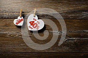 Big sale on hearts hanging on rope with clothespins over the wooden background. Forty percent discount promotion written on white