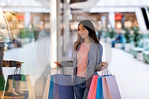 Big sales and discount concept. Portrait of beautiful young Asian woman with colorful gift bags shopping at city mall