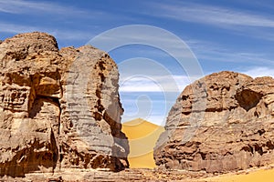 Big sand dune between two stone mountains in the Sahara Desert of Tadrart Rouge, Djanet, Algeria.