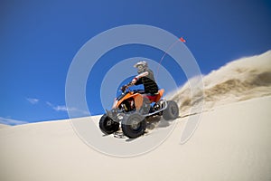 Big sand spray from ATV quadbike rider in the dune