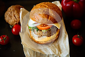 Big sandwich - hamburger with juicy chicken burger, cheese, tomato, and red onion on wooden background