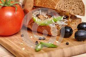 Big sandwich on wooden cutting board with ingridients