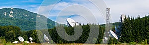 Big satellite dish antennas hidden in green pine tree forest. Satellite Communication Center in Cheia, Prahova, Romania photo