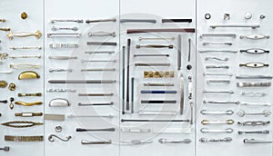 Big selection of handles cabinets parts on a white background shop window. samples of Metal and Stainless Steel handle styles on