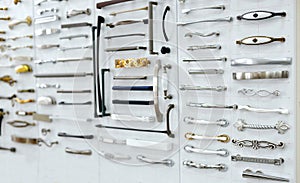 Big selection of handles cabinets parts on a white background shop window. samples of Metal and Stainless Steel handle styles on