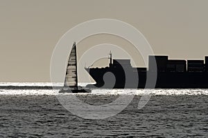 Big ship and small sail ship silhouette on sea horizon line