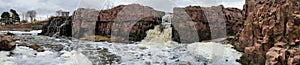 The Big Sioux River flows over rocks in Sioux Falls South Dakota with views of wildlife, ruins, park paths, train track bridge, tr