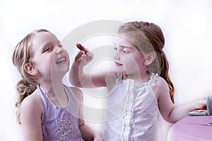 Big sister applying makeup to little sister