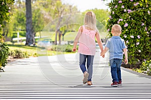 Big Sister and Brother Holding Hands And Walking At The Park photo