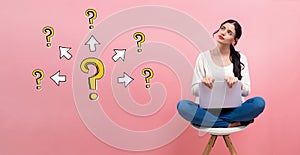 Big and small question marks with arrows with woman using a laptop