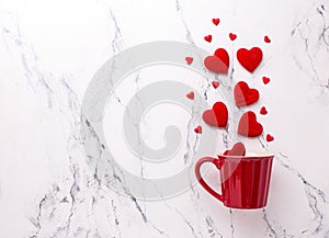 Big and small red hearts  and red cup on  white marble background.