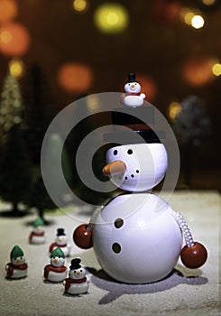 Big and small snowman stand on ice ground with Christmas light background