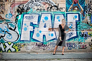 Big smile of an elegant lady in front of a wall with graffiti. A wall vandalized with street graffiti art.