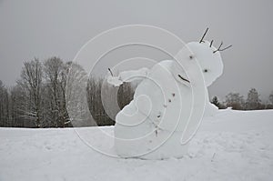 A big snowman has a sloping body that looks like he is falling, not limping, and has back pain. going away the winter is over. for