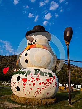 Big snowman stand on farm with blue sky