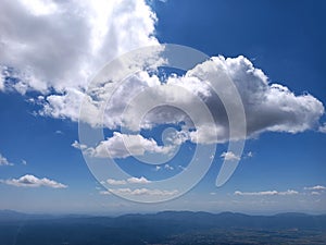 Big soft clouds on the blue sky in summer, below are the mountains photo