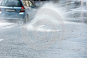 Big splashes of rainwater from car wheels during heavy rain