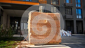 Big stack or red construction bricks on wooden pallet on building site