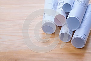 Big stack of rolls blueprints on wooden board with