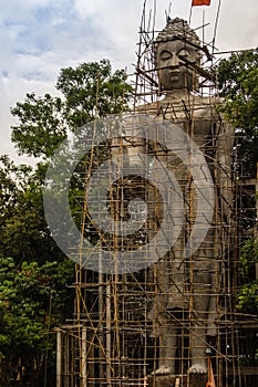 Big stand Buddha image is under construction with full of scaffolding around in the Buddhist temple, Thailand
