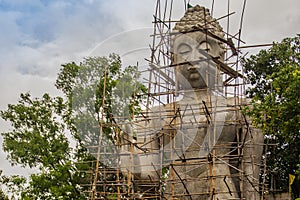 Big stand Buddha image is under construction with full of scaffolding around in the Buddhist temple, Thailand