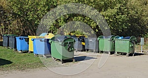 Big standard  isolated plastic trash bins are located near forest