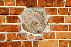 Big stone in red brick wall. Architecture closeup