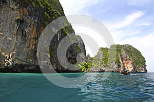 Big stone or rock mountain or island and long tail boat on sea with blue sky and white cloud background at Krabi, Thailand.