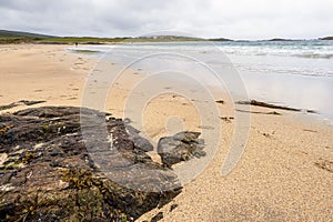 Big stone on a sandy beach in focus. Irish nature landscape, Atlantic ocean,West coast of Ireland. Cloudy sky