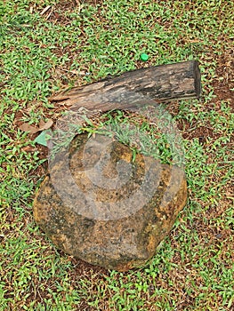 A big stone and tree log on a green grass yard