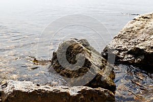 Big stones lie on sea beach. Coast. Nature background. Water with waves