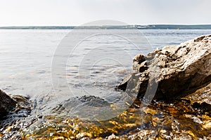 Big stones lie on sea beach. Coast. Nature background. Water with waves