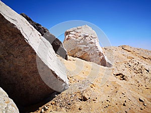 Big stones on the sea coast with white sand beach, bay, sea and blue sky