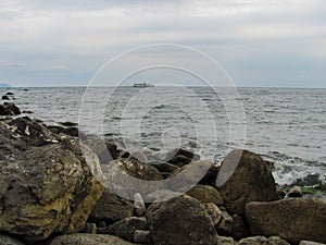 Big stones on the seaside and the ship away on the horizon