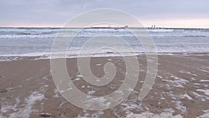 Big stormy waves in the sea. Beautiful seascape with pier, sandy beach at sunset.