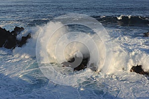 Big and strong waves breaking on the volcanic rocks on the Atlantic Ocean on coastline and seashore of Madeira Island, Portugal