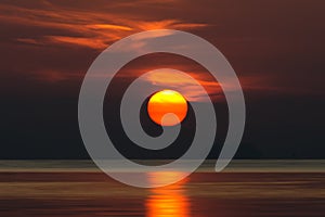 Big sun and orange cloud in sunset sky on the lake