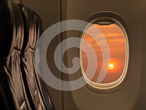 Big sun at sunset sky from airplane window. Travelling by airplane seat near window enjoying beautiful sunset. Sunset through