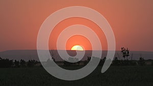 Big Sunrise Sunset Big Red Hot Sun in Warm Air Distortion Above Horizon Seamless. Sun behind the hill