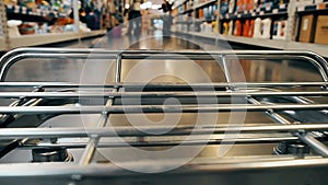 Big supermarket shopping cart in motion goes between blurred shelves. Color graded