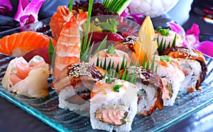 Big sushi set with maki, nigiri, dragon rolls. Sushi with salmon, eel, tuna, raw fish, on a blue, glass plate.