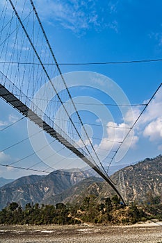 A big suspension bridge crossing a rough mountain river. View from underbridge