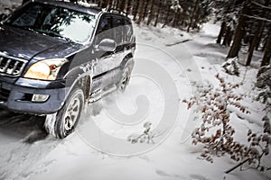 Big suv car going fast on a snow covered forest road