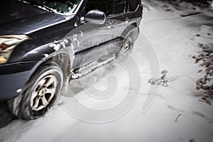 Big suv car going fast on a snow covered forest road