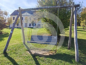 Big swing park bench in landscape park with manor house in background