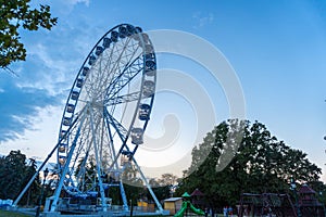 Big tall white Ferris wheel in front of a perfect blue sky
