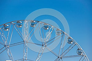 Big, tall white Ferris wheel in front of a perfect blue sky