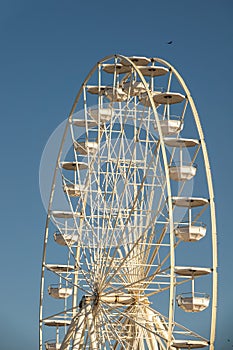 Big, tall white Ferris wheel. Modern ferris wheel at carnival with blue sky