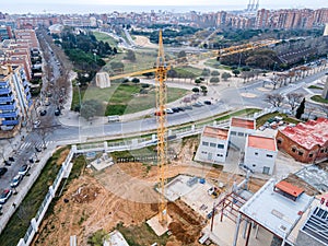 Big tall yellow tower crane over the buildings at a construction site